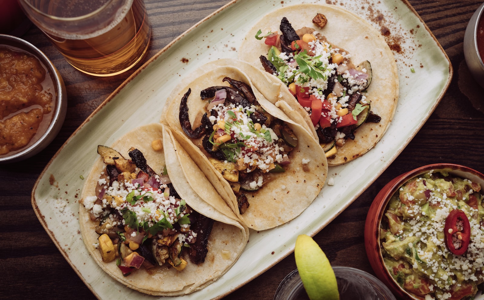 Three loaded street tacos on a platter with guacamole